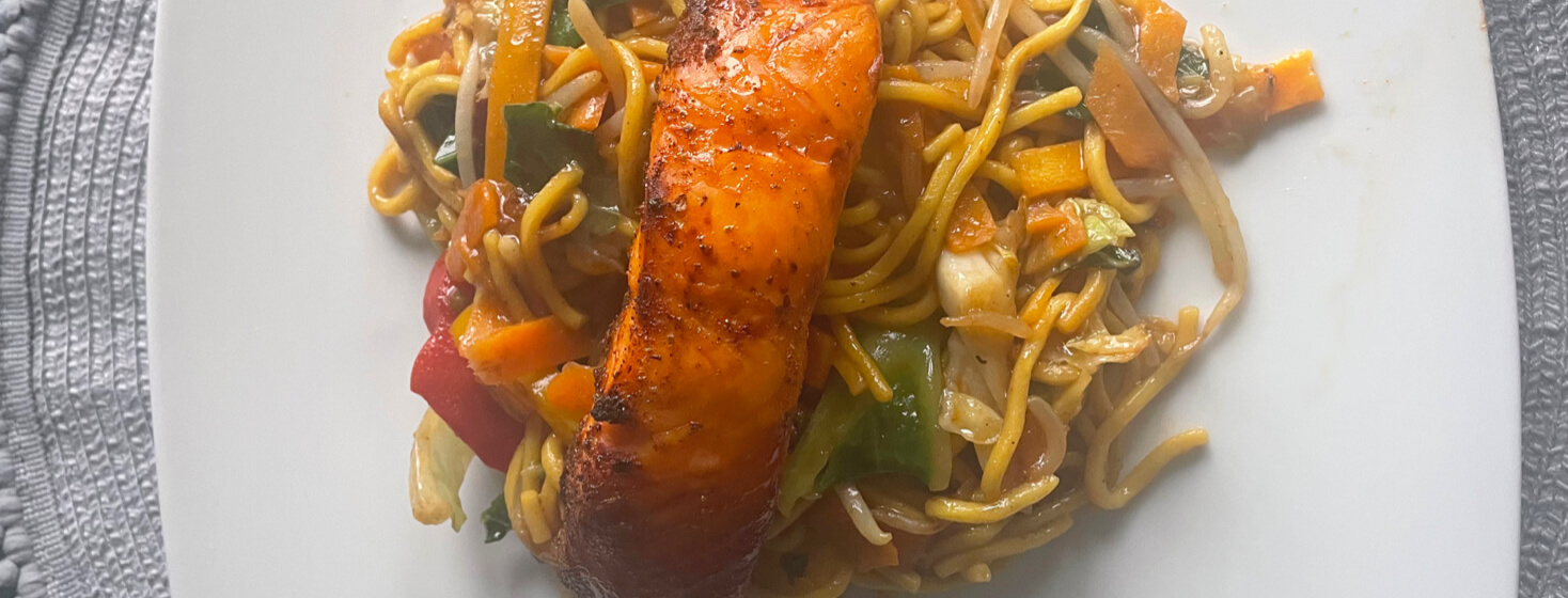 Salmon stirfry on top of noodles and vegetables
