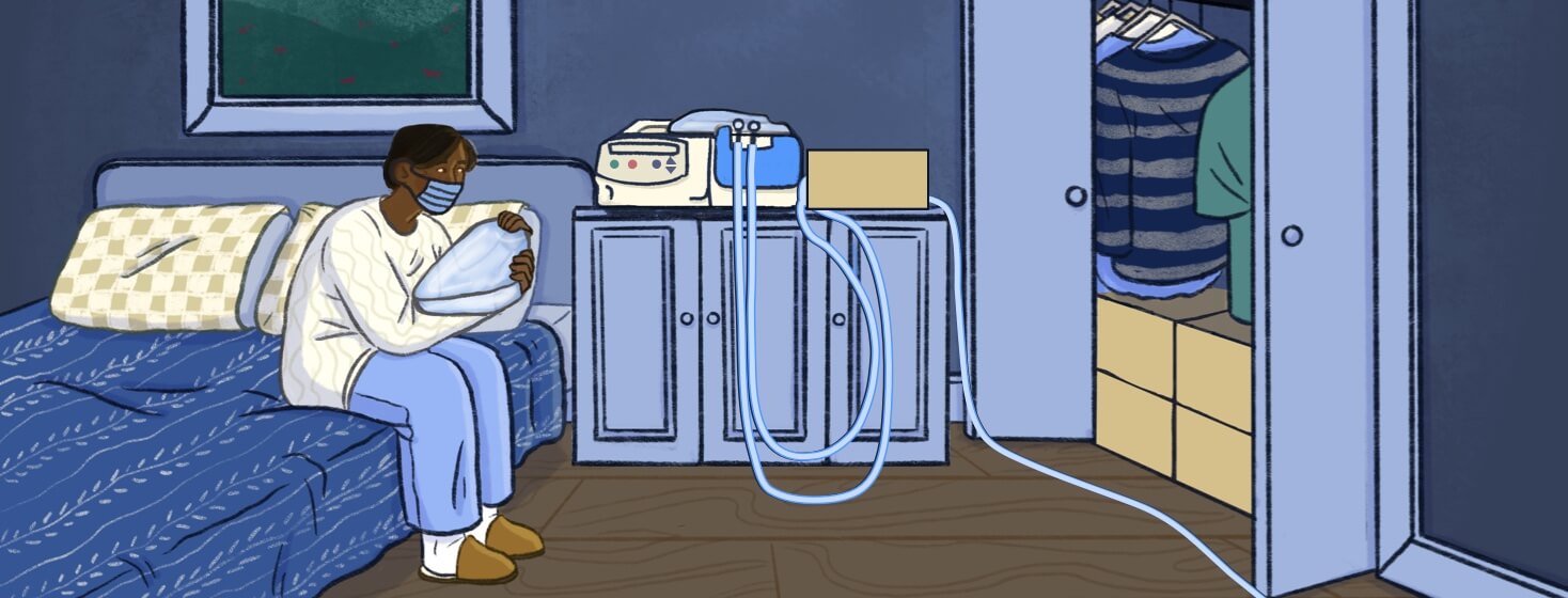 A person wearing a mask sits on the side of their bed preparing supplies for Peritoneal Dialysis.